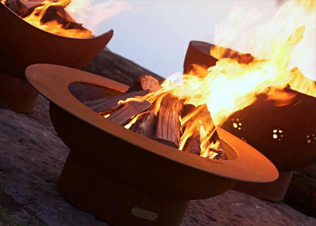 Wood fire pit with round side cutout and burning firewood, flames visible