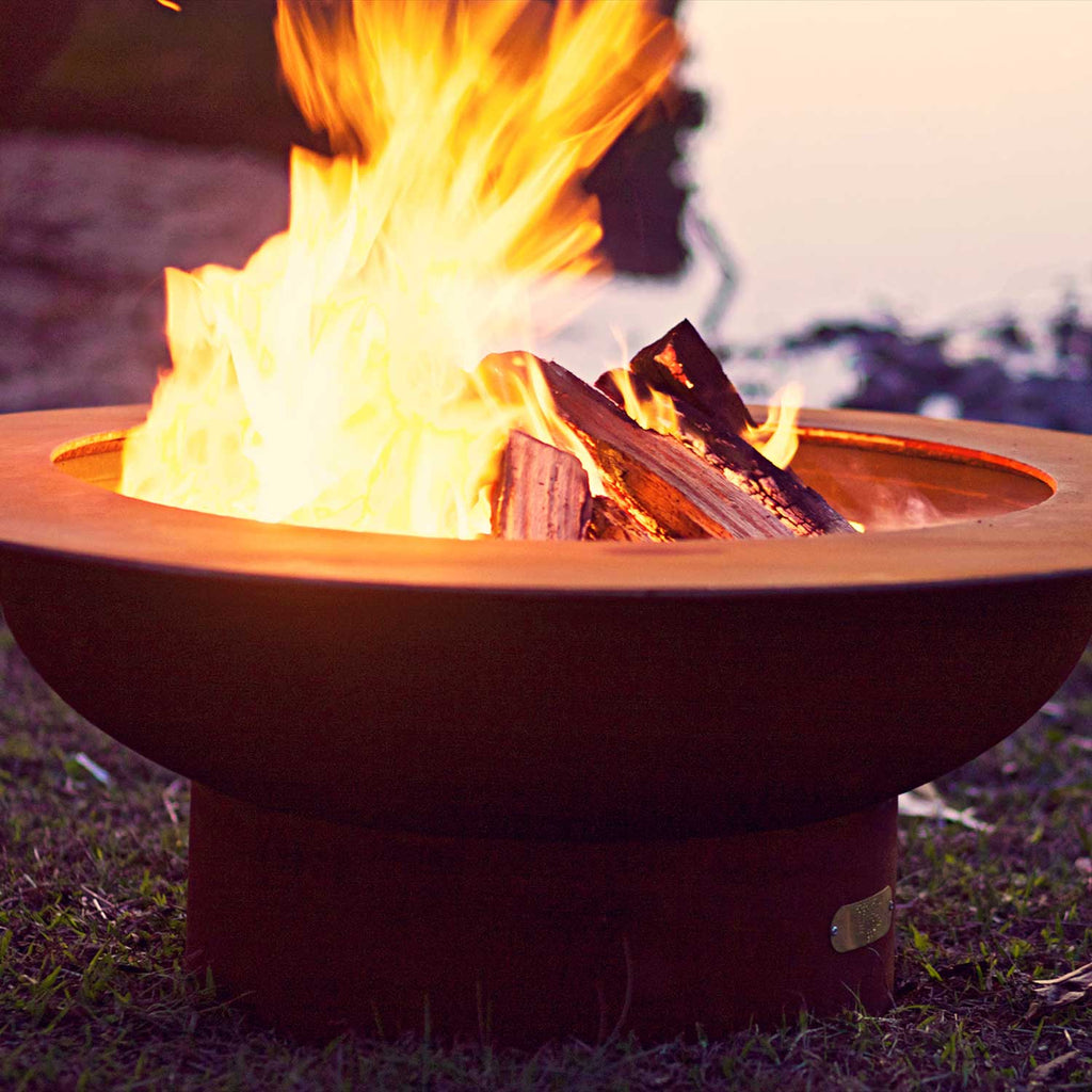 Burning wood fire pit with open circular bowl and large flame