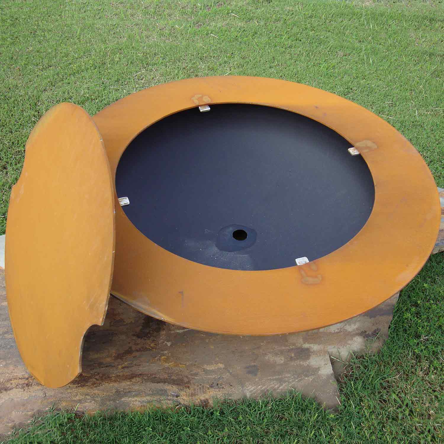 Round gas fire pit with hinged lid open, black burner interior and tan outer body