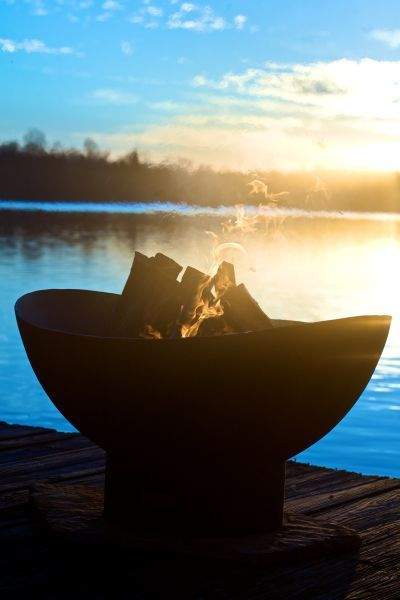 Black wood fire pit bowl with logs and small flames at top