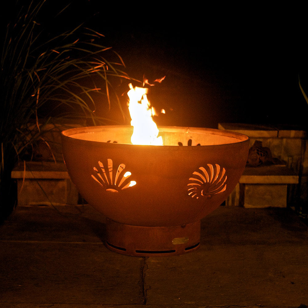 Bronze gas fire pit bowl with two sea-creature cutouts and tall flames
