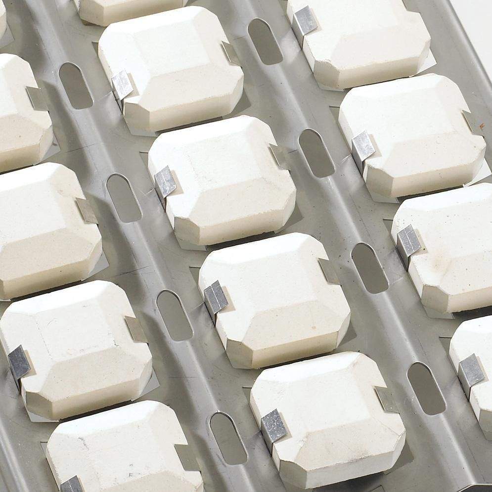 Gas grill burner area with multiple white ceramic briquette blocks