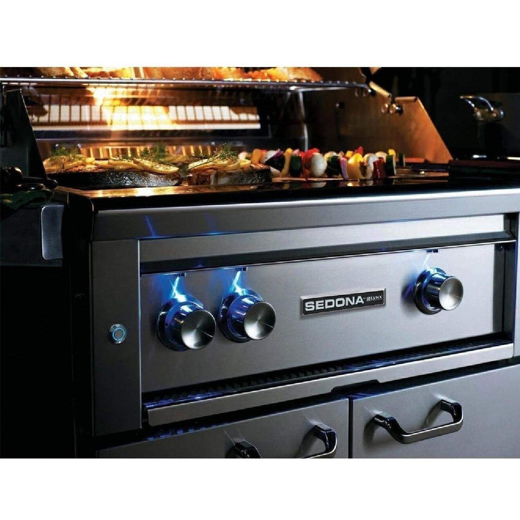 Gas grill with lit burner flames and cooking food on the grate