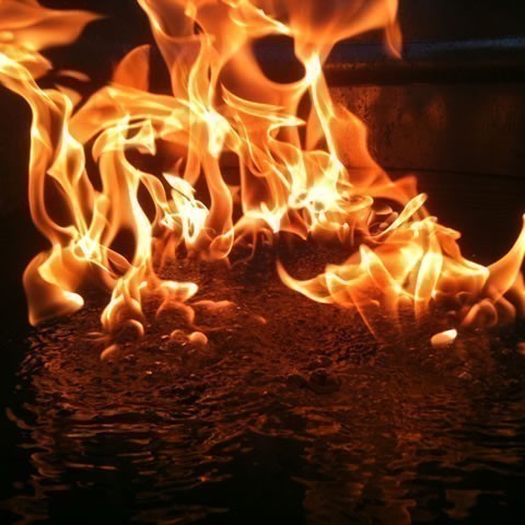 Close view of flames burning at the edge of a wet surface