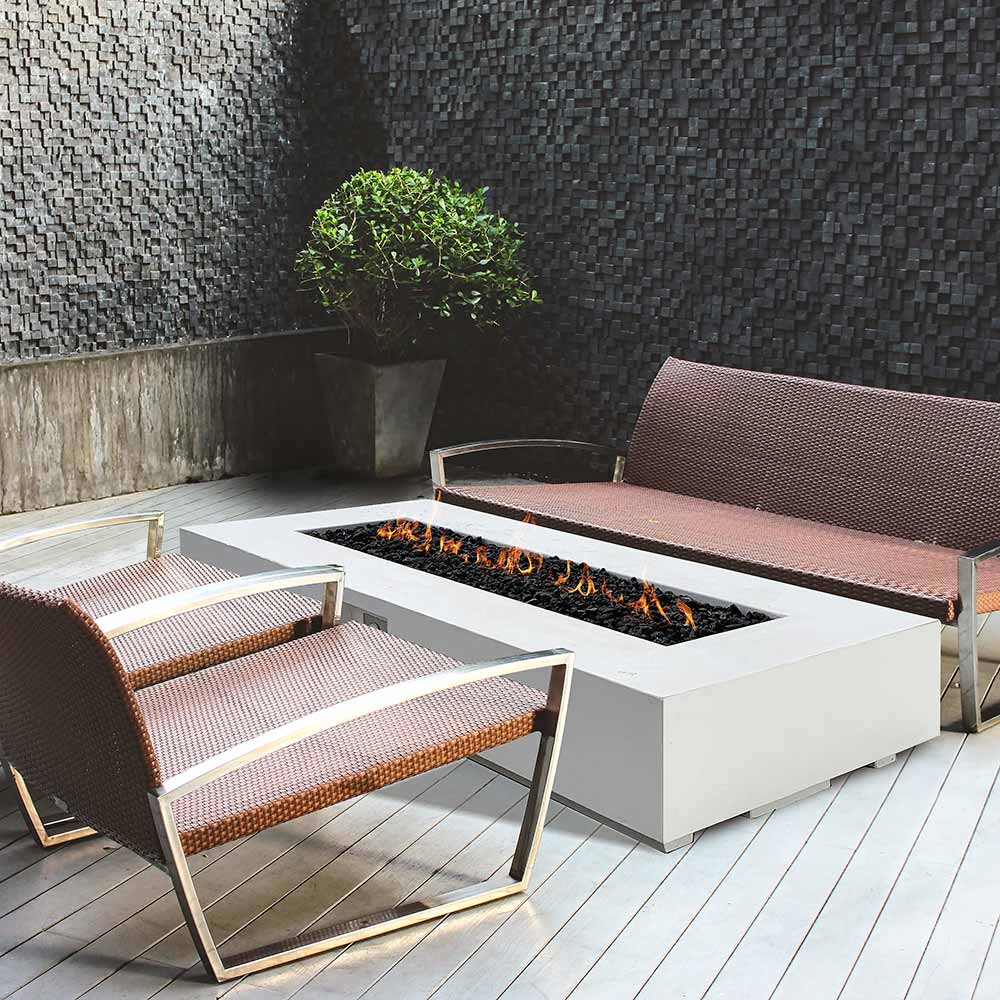 Rectangular outdoor gas fire pit with flames and nearby cushioned lounge seating