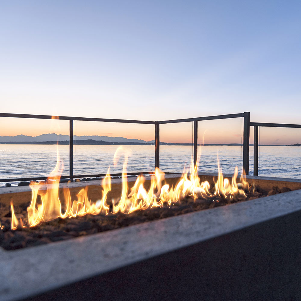 Concrete gas fire pit with glowing flames along the burner bed