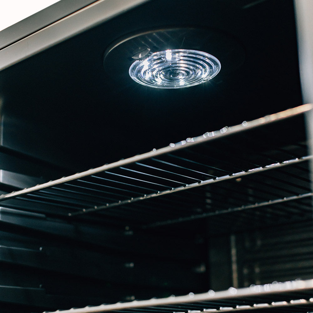 Refrigerator interior ceiling light above wire shelves.