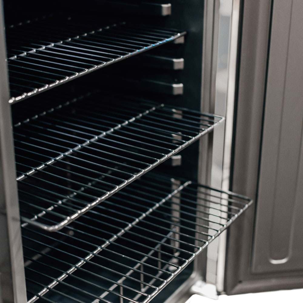 Wire shelf inside outdoor fridge with black interior walls and door frame edge.
