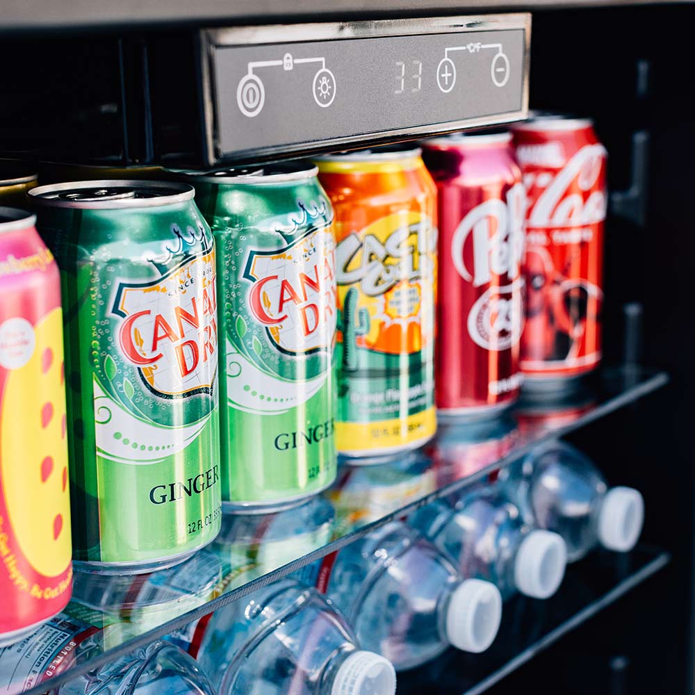 Fridge interior shelf with rows of beverage cans and bottles