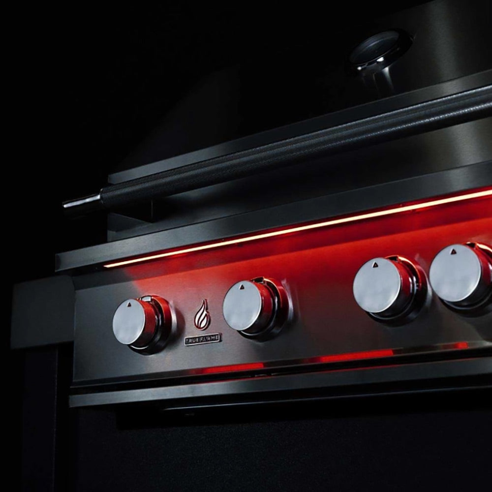 Stainless gas grill front panel with round control knobs and glowing red indicators