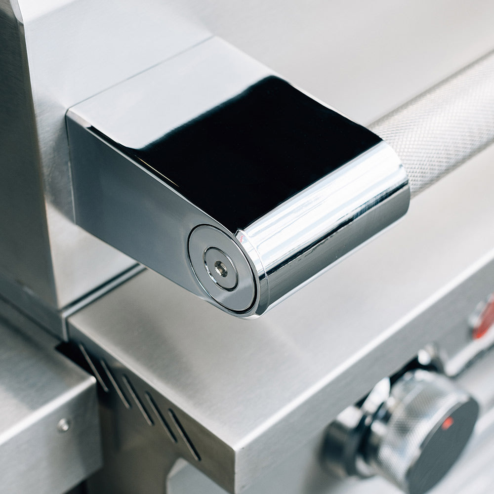 Stainless steel side shelf with chrome handle on a gas grill