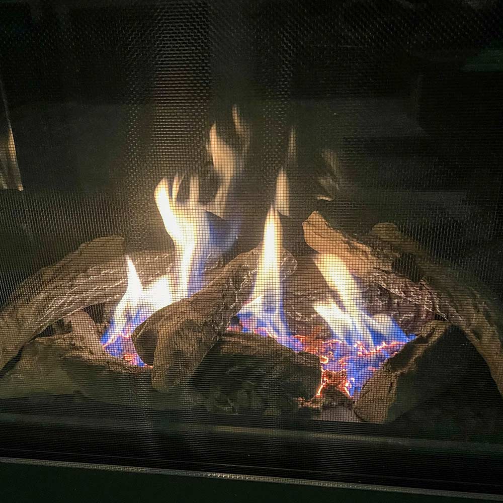 Close-up of burning log set inside glass-front direct vent gas fireplace