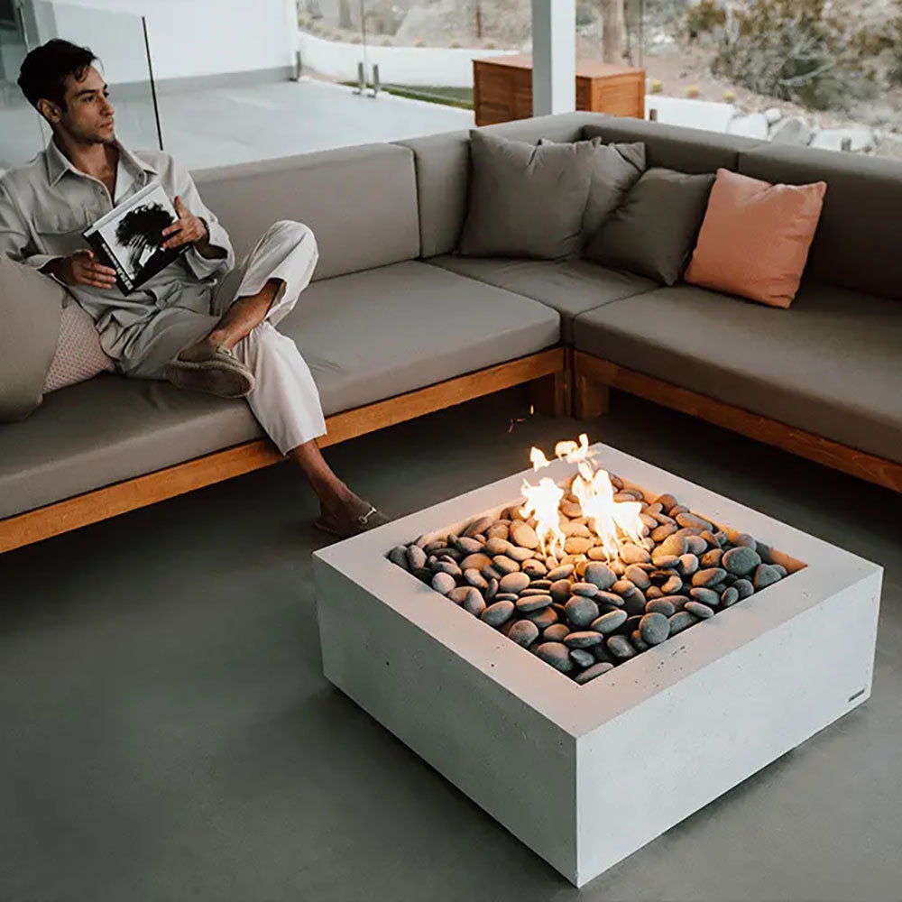 Square concrete gas fire pit with pebble stone bed and flames, framed by the base