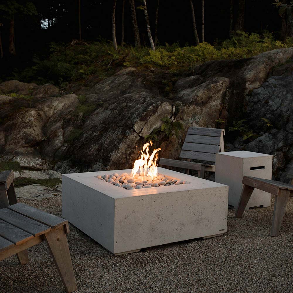 Square concrete gas fire pit with flames over light gray stones