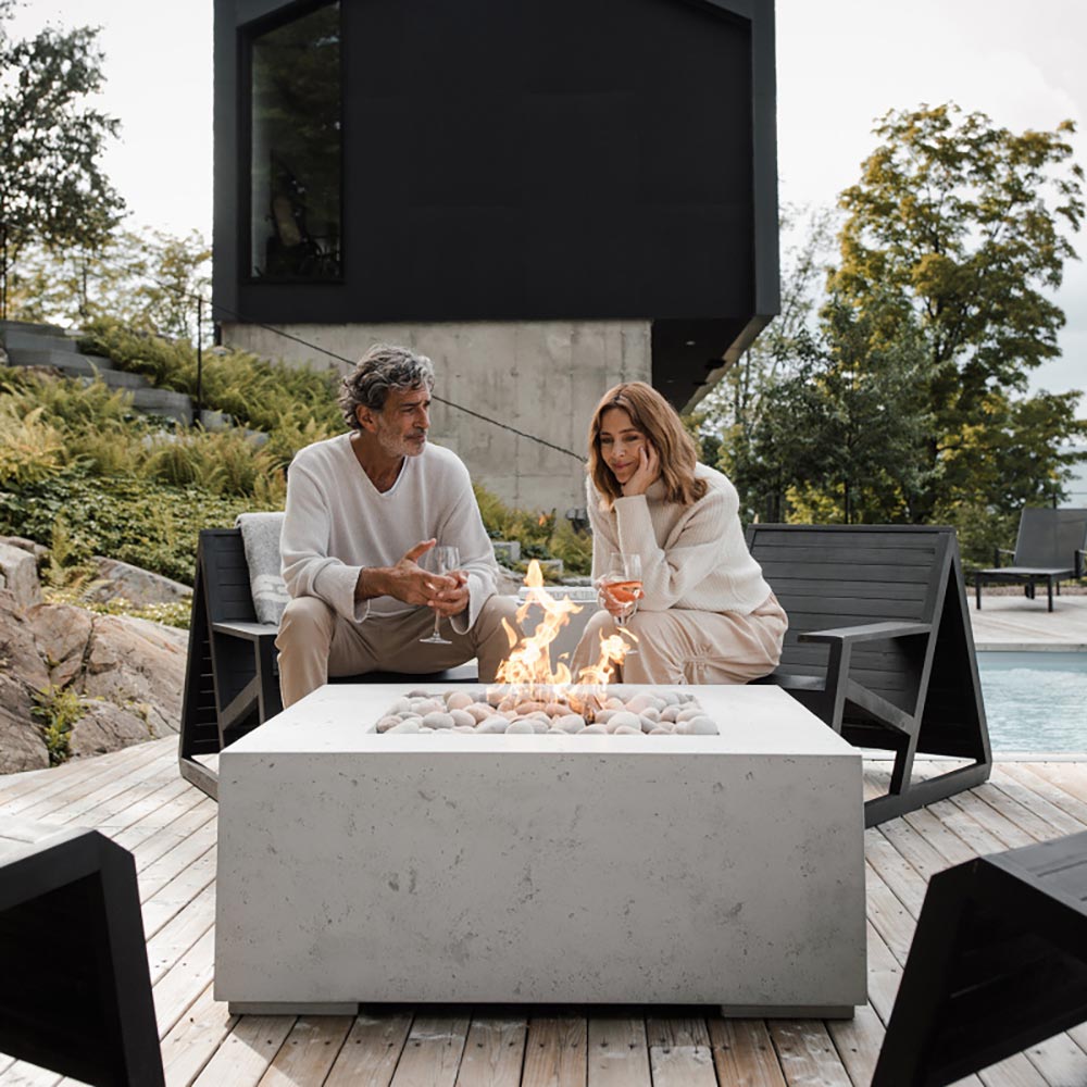 Square concrete gas fire pit with flames and gray stones in open top