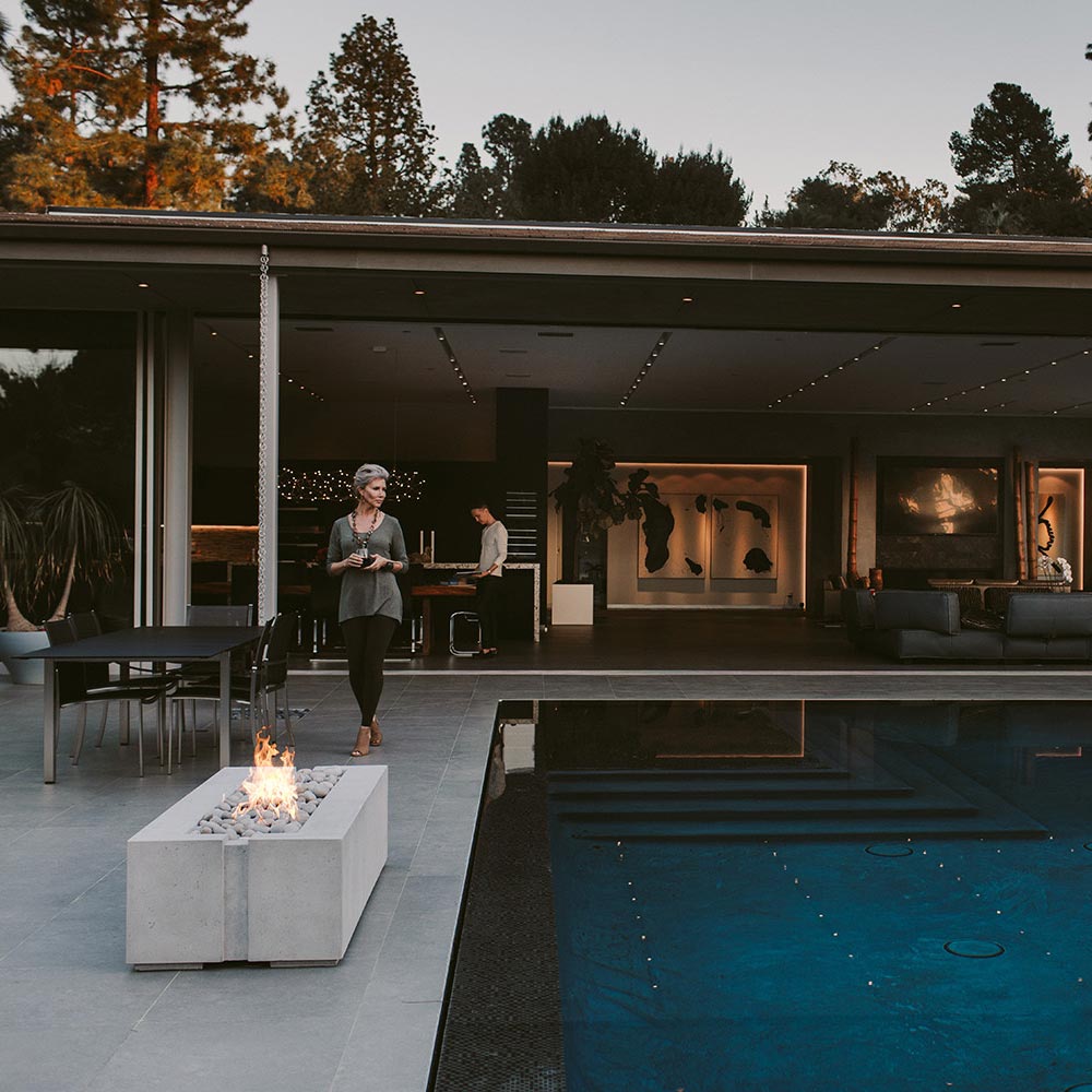 Concrete gas fire pit with flame, built-in rectangular enclosure on outdoor patio