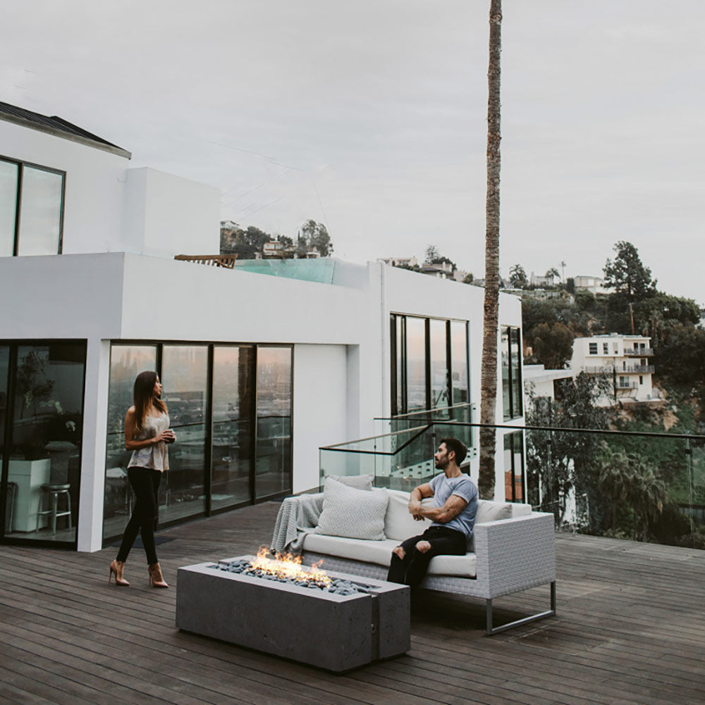 Rectangular concrete gas fire pit with visible flame media on outdoor deck