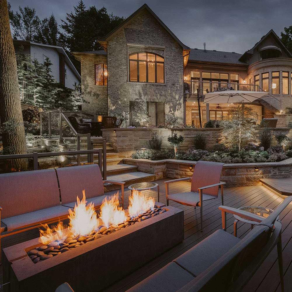 Outdoor lightweight concrete gas fire pit with flames in patio seating area