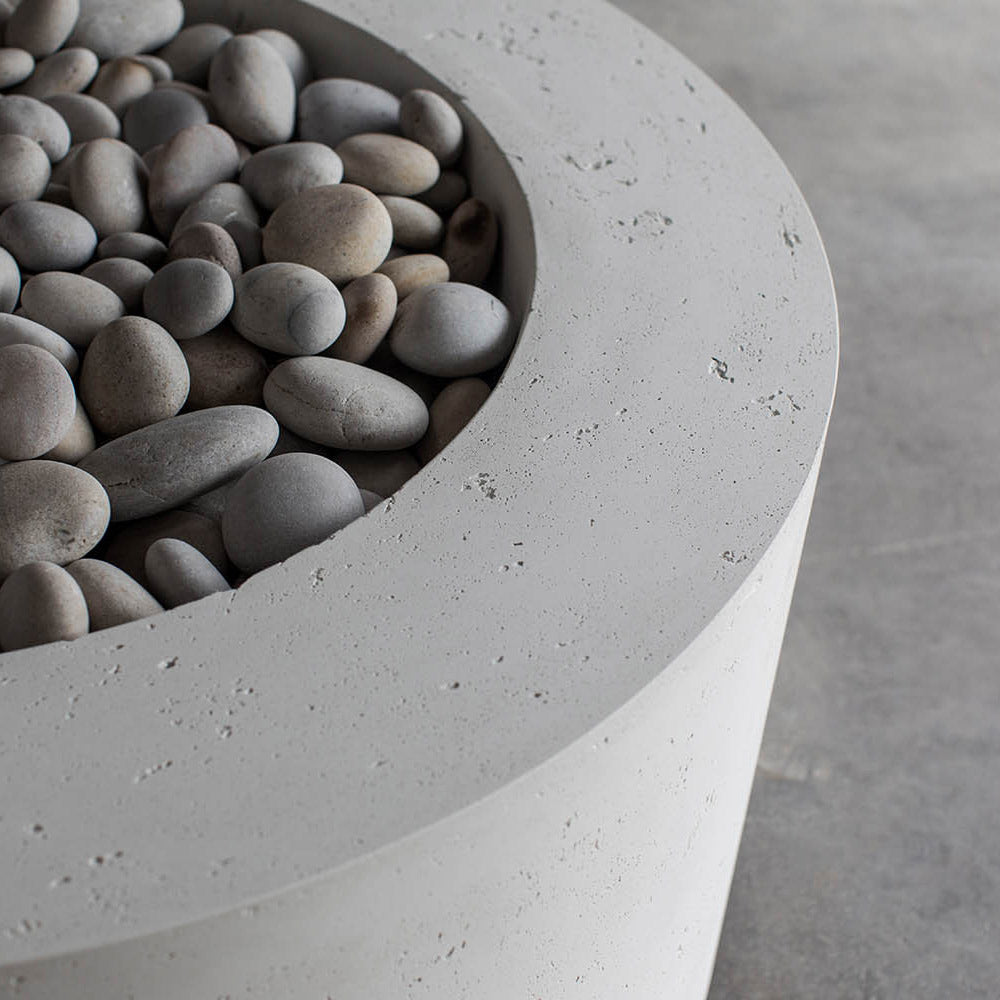 Close-up of smooth river stones inside a light gray concrete fire pit