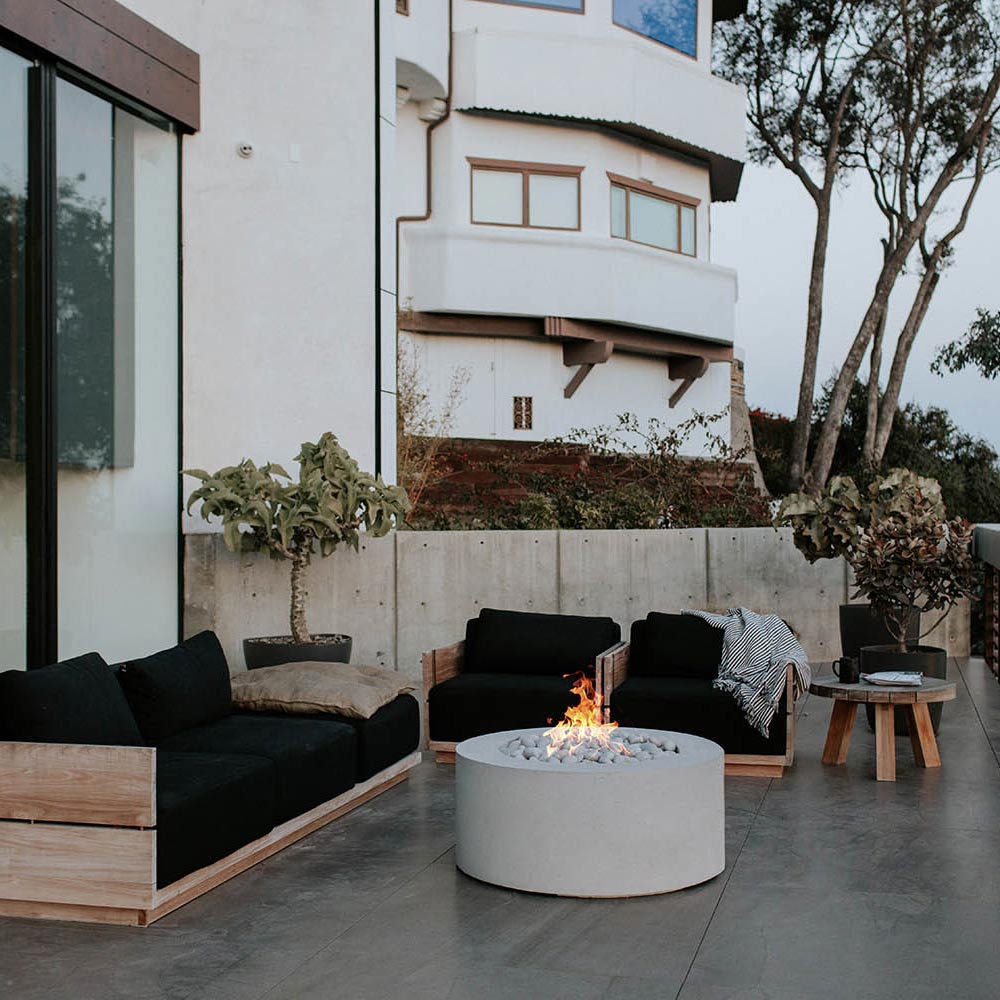 Light gray round concrete gas fire pit with flames in the center