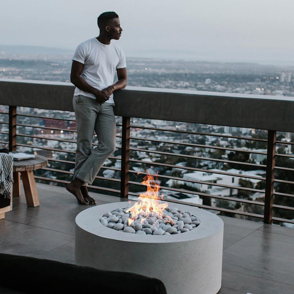 Light gray round concrete gas fire pit with flames and smooth stones
