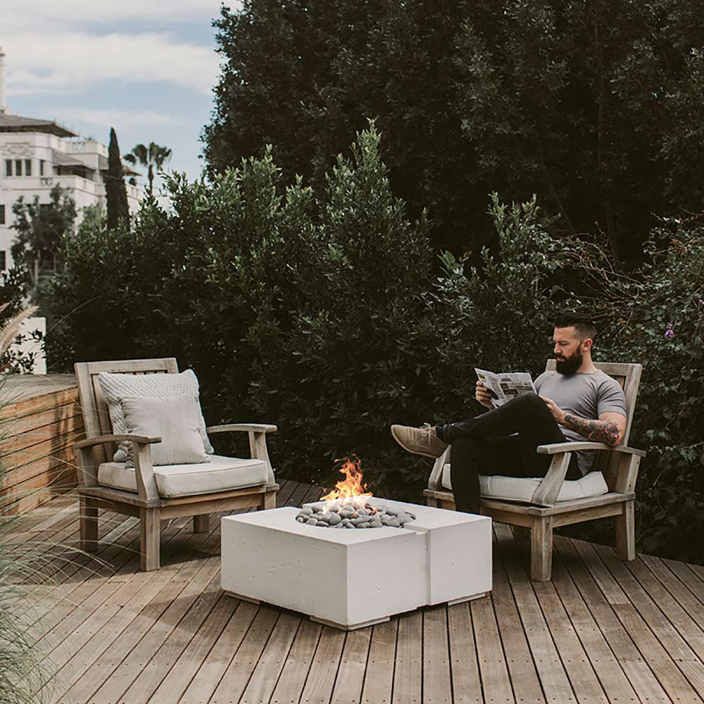 Square concrete gas fire pit with visible flame on an outdoor patio deck