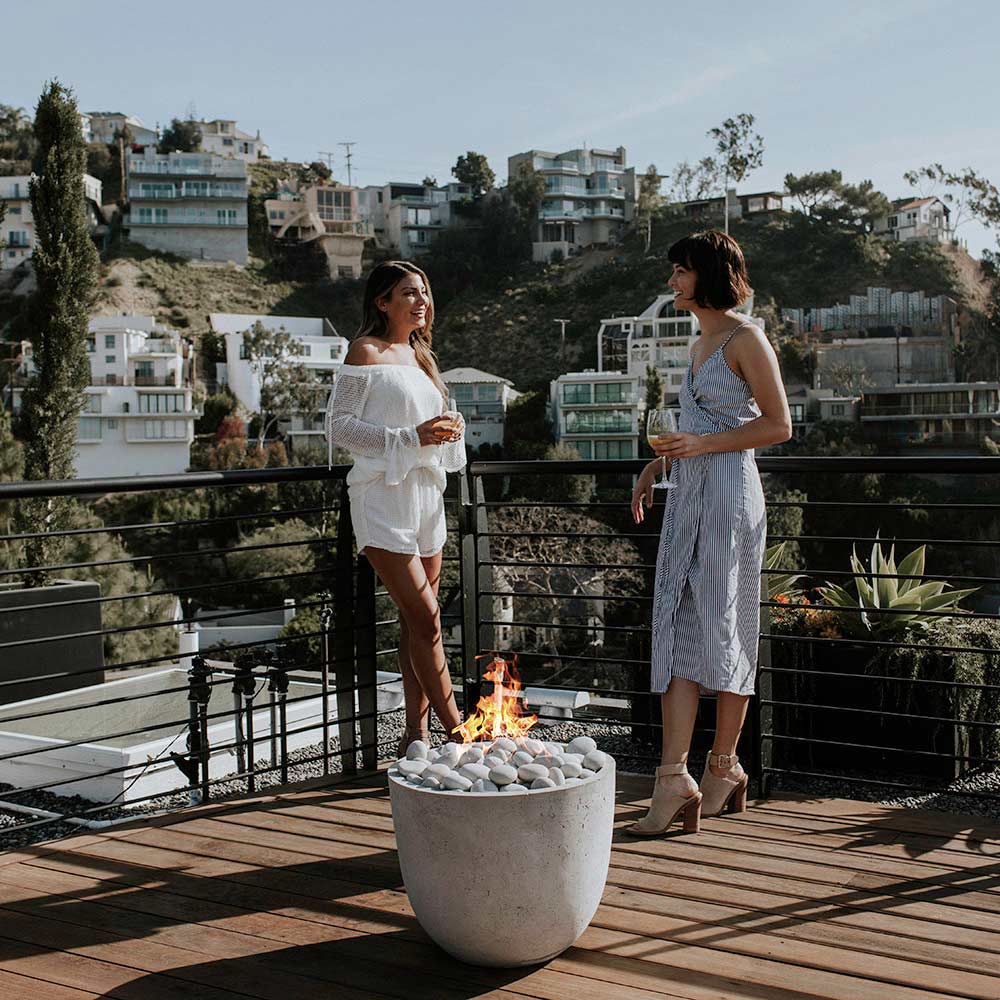 Outdoor concrete gas fire bowl with flames and light gray pebble media