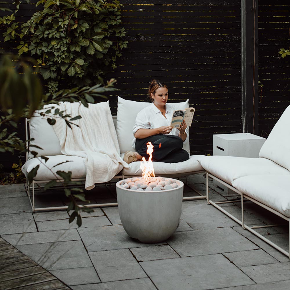 Outdoor concrete gas fire bowl with flames and light gray pebble media