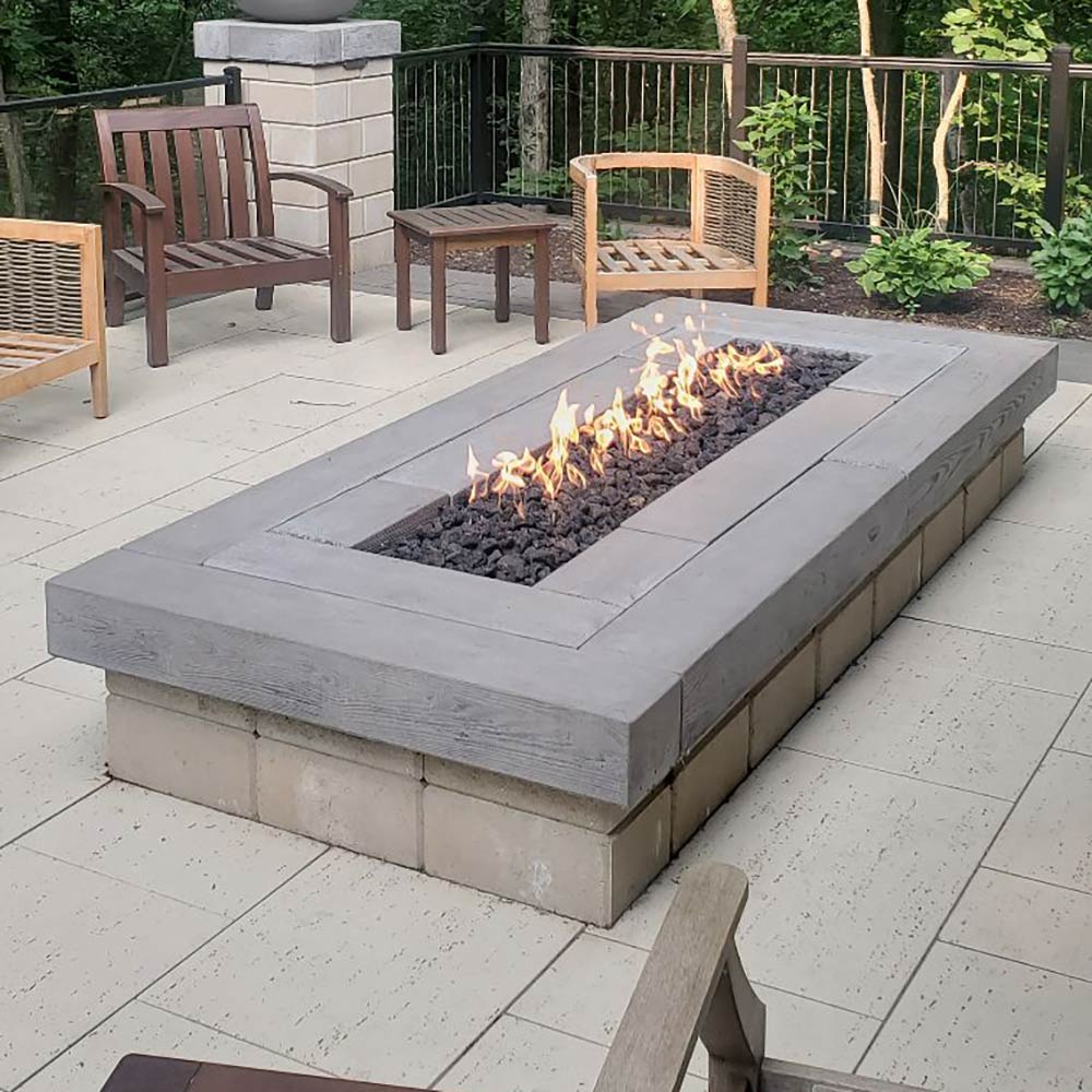 Rectangular concrete fire pit with lit flames in a long built-in burner channel