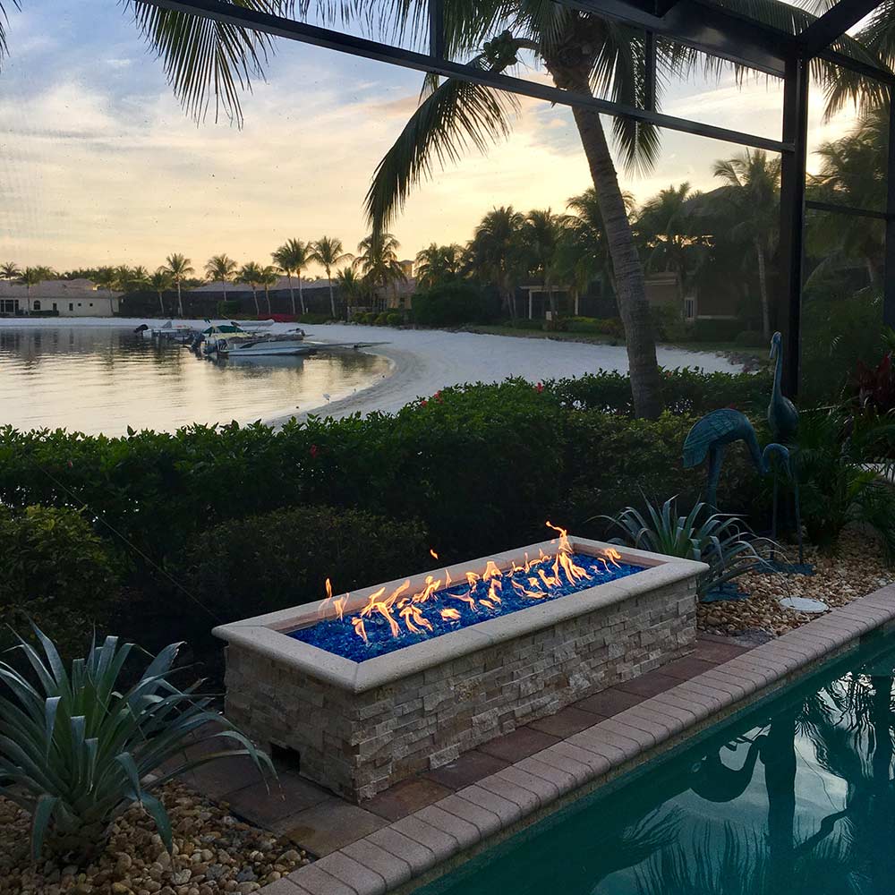 Rectangular gas fire pit with electronic ignition burning flames outdoors by the pool