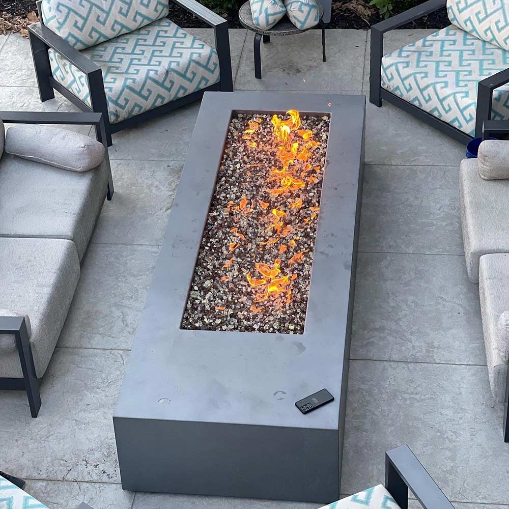 Rectangular gas fire pit flame bed with electronic ignition in an outdoor lounge patio