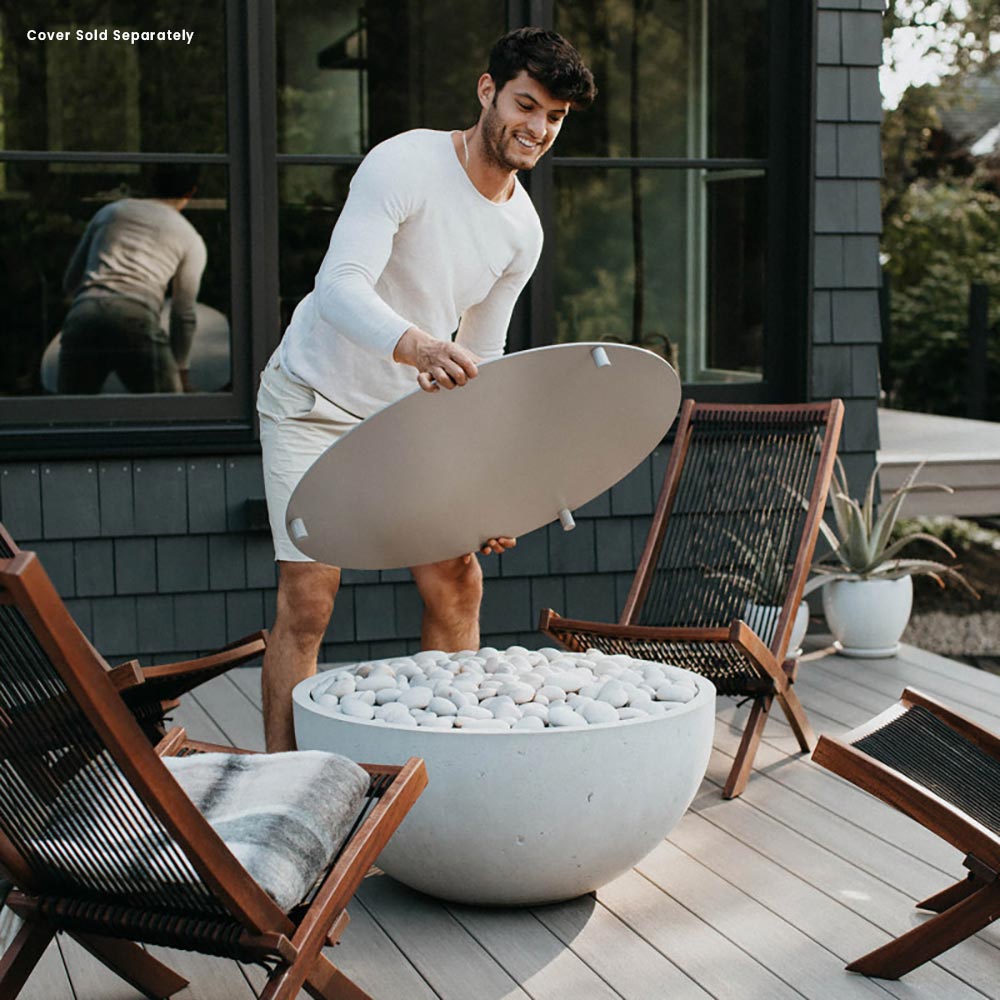 Concrete gas fire bowl with flame and light gray stones on an outdoor deck