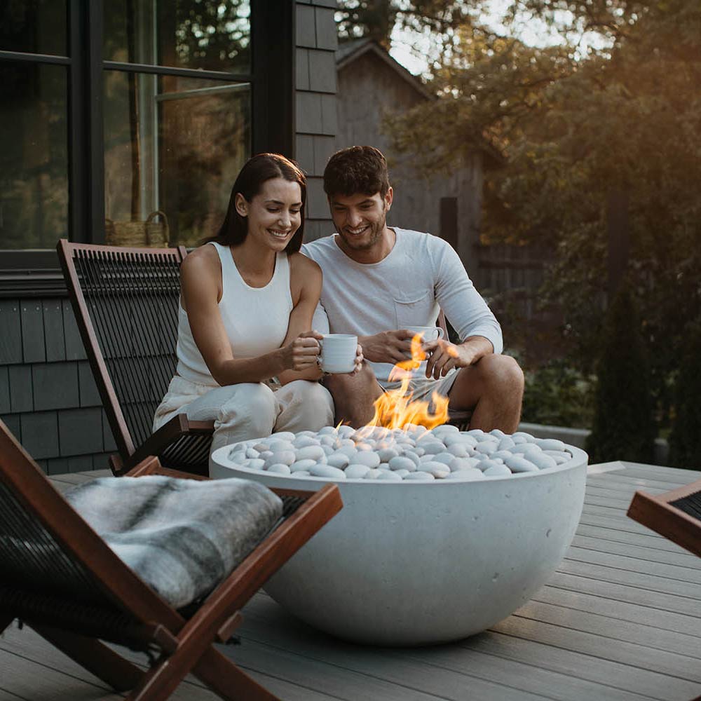 Outdoor concrete gas fire bowl with flames and light gray stones