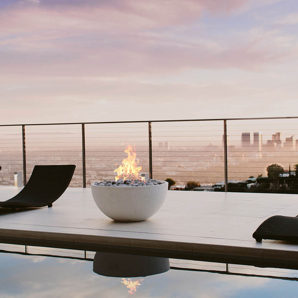 Concrete gas fire bowl with burning flames on a modern patio surface