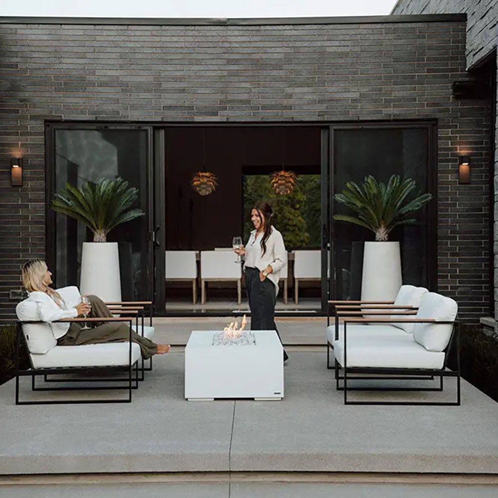 Lightweight concrete gas fire pit on patio with flames and pebble-filled firebox