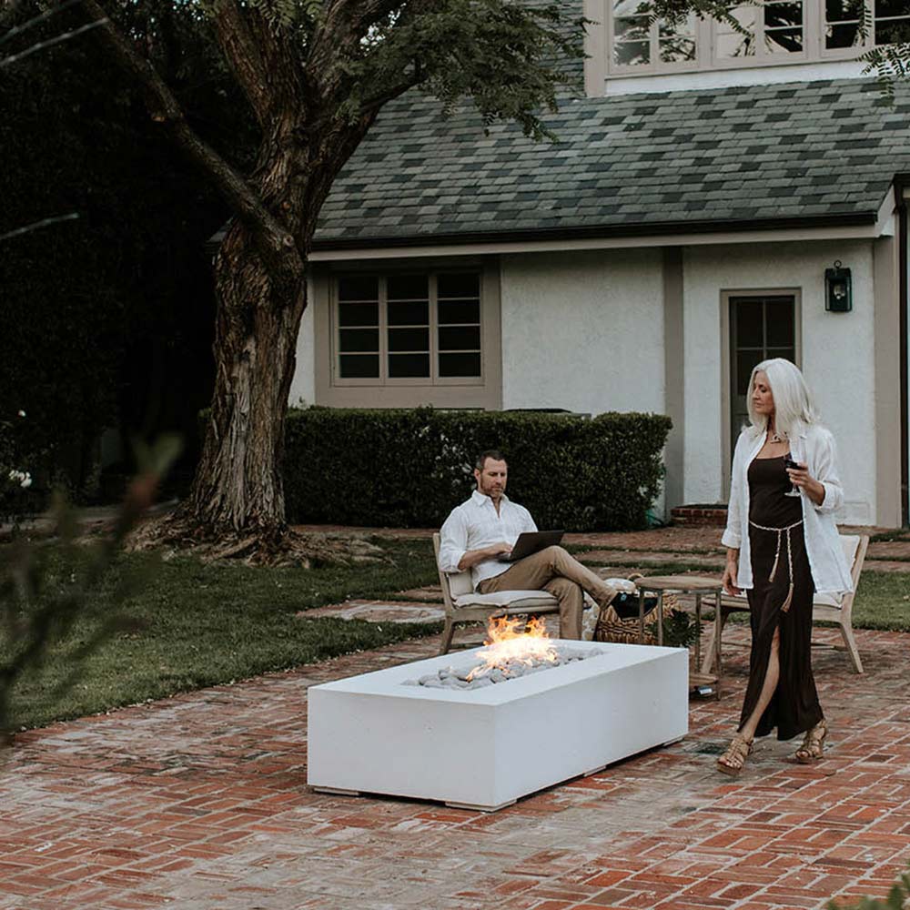 Lightweight concrete gas fire pit in a backyard patio setting with small flames.