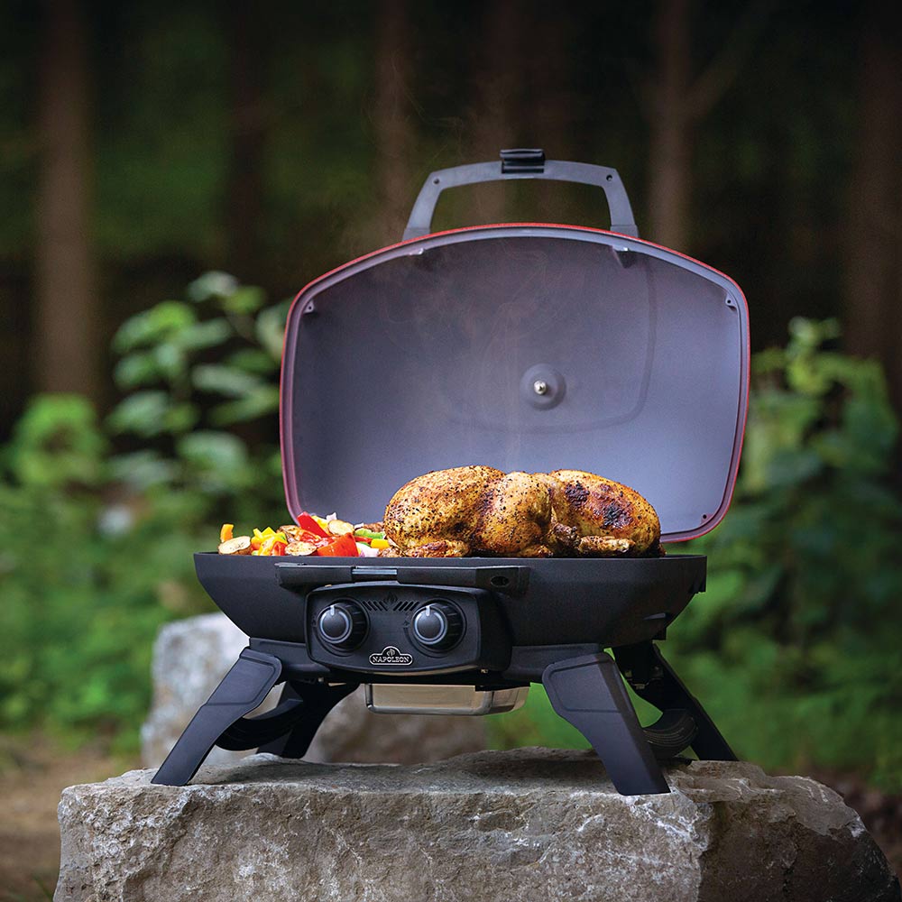 Portable gas grill with open red lid, front burner knobs, and cooking chamber view