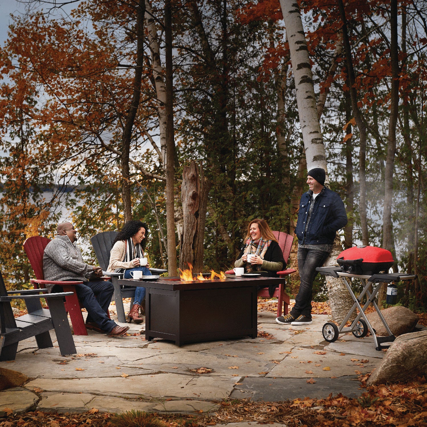 Portable propane grill on a scissor cart with people gathered outdoors