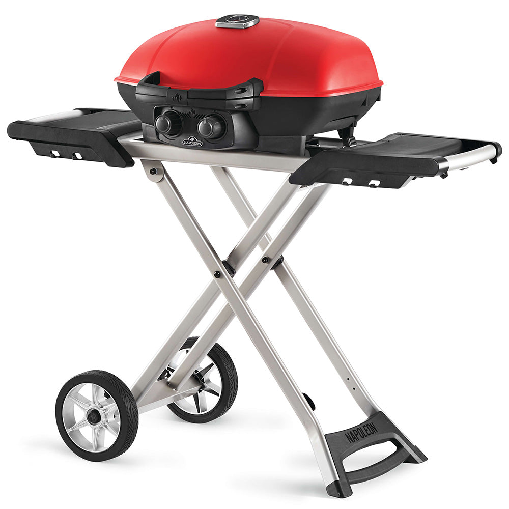 Portable propane grill with red lid, black lid handle, and side shelves on silver stand.