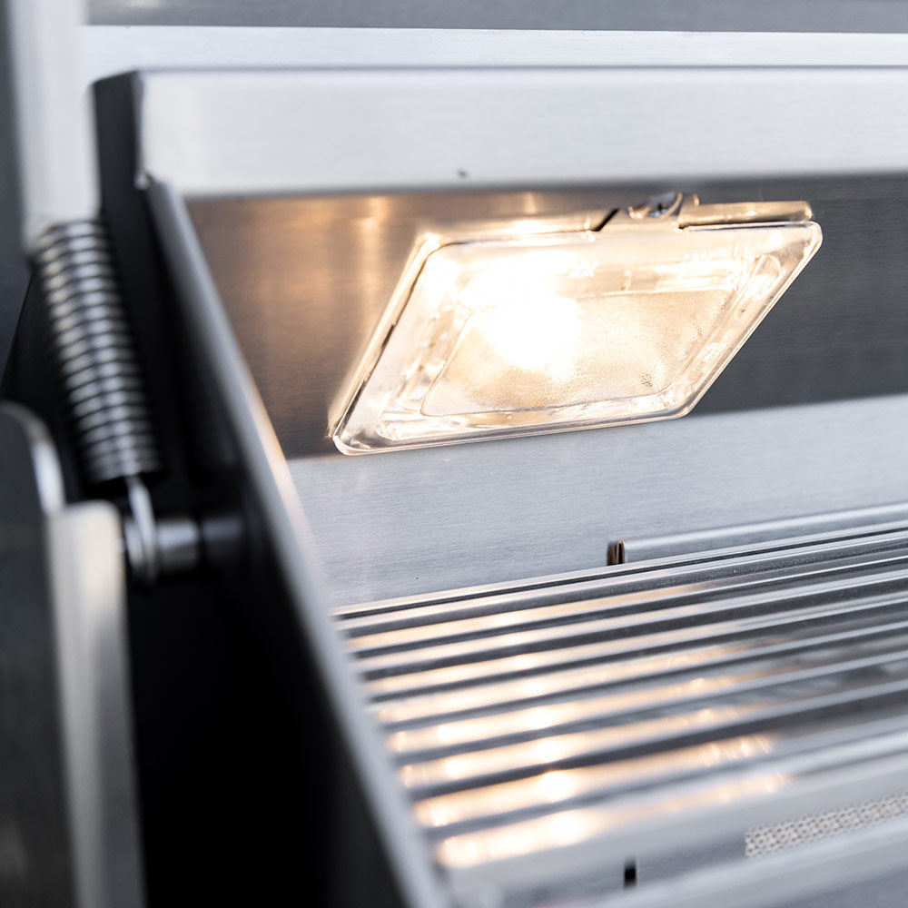 Gas grill interior with lit lamp and stainless housing, close-up