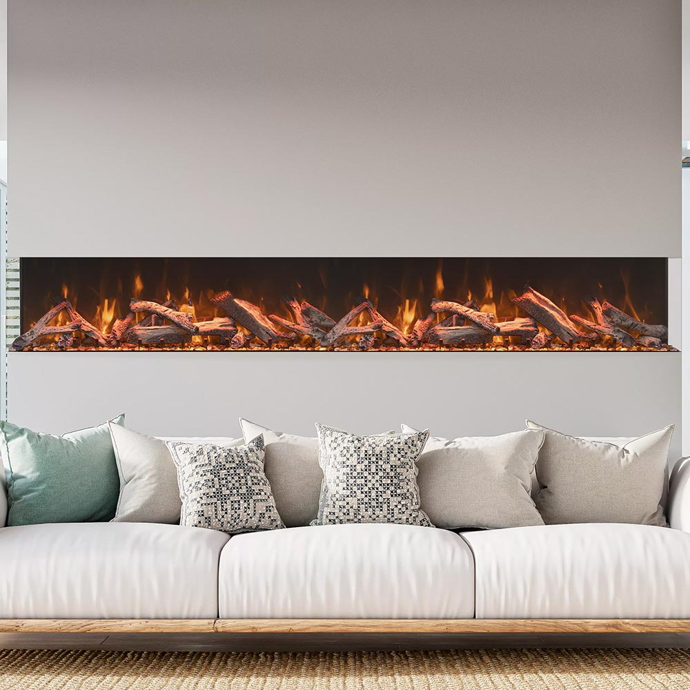 Three-sided electric fireplace above white sofa with burning log flame display