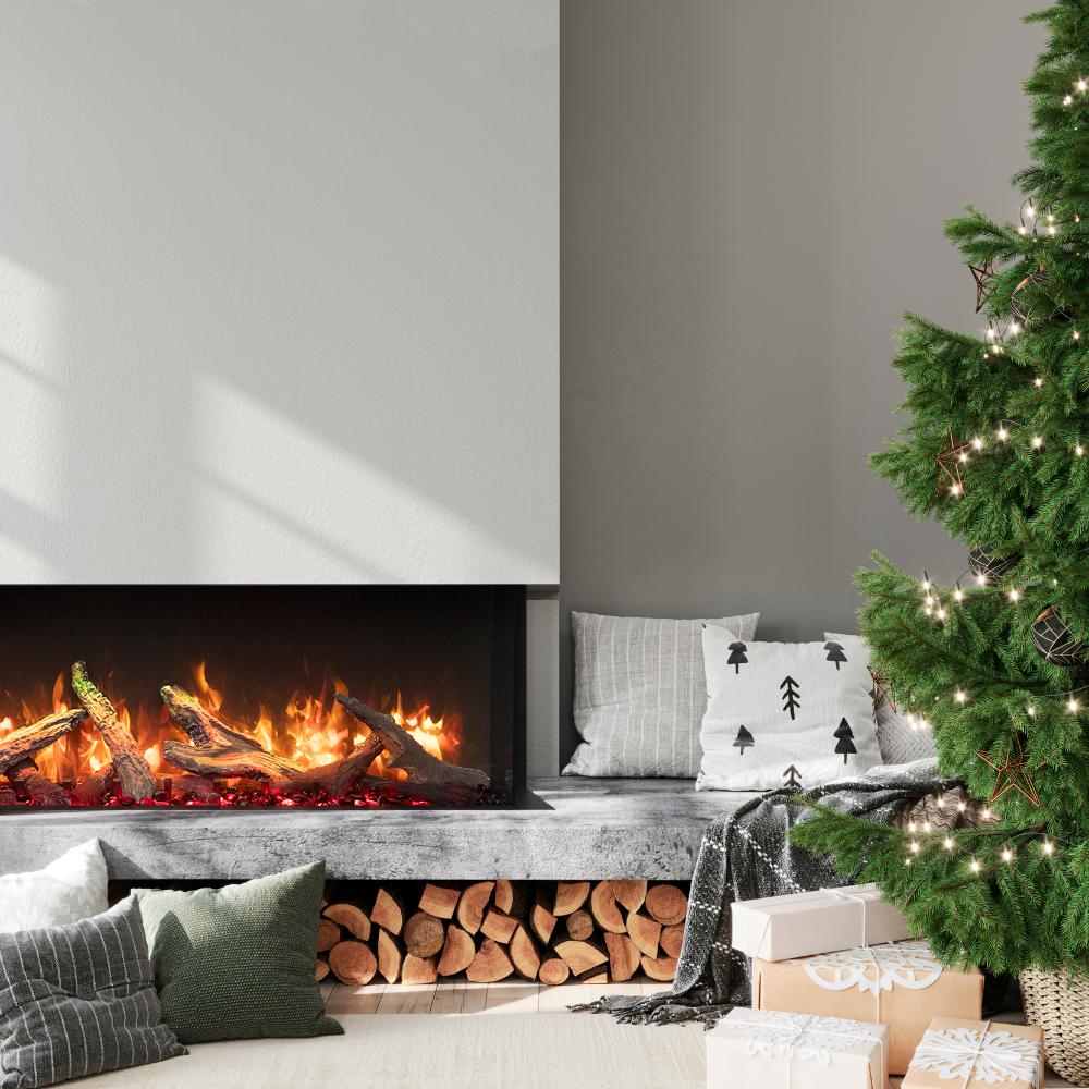 Built-in electric fireplace with flames beside stacked logs and a lit Christmas tree