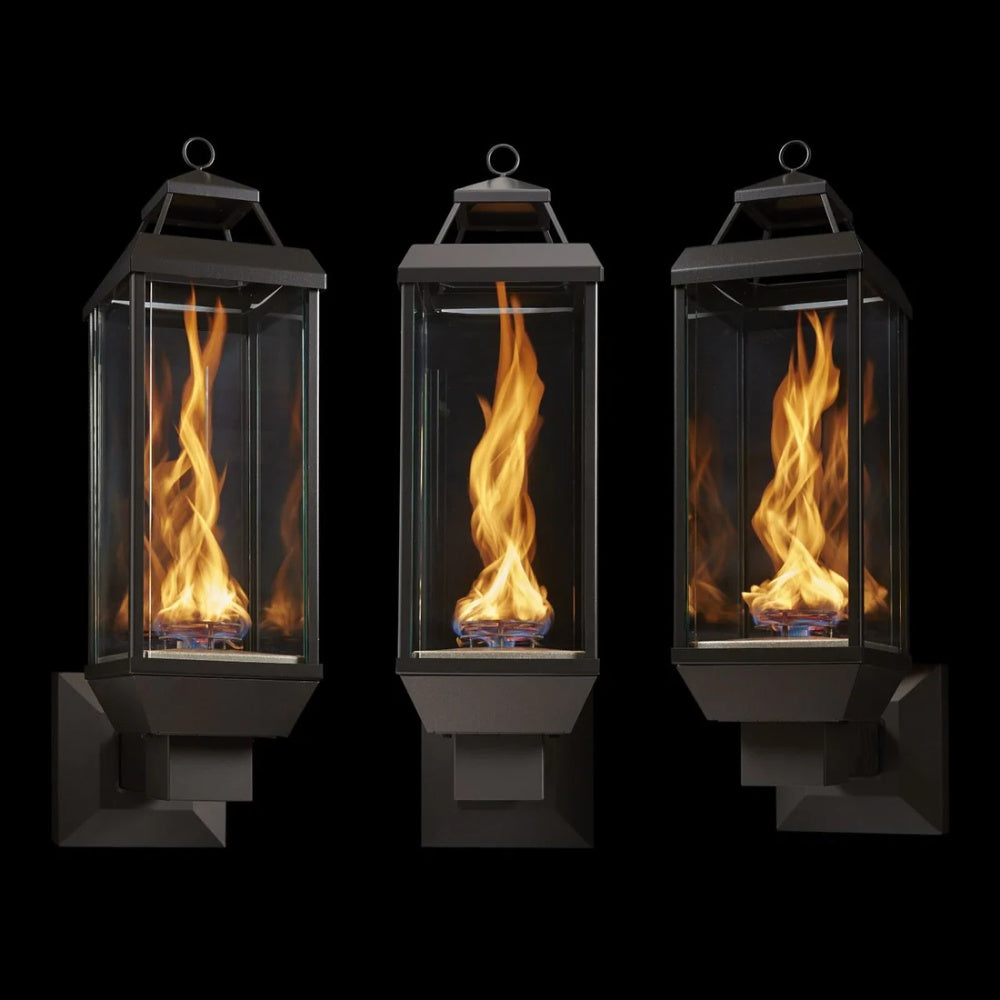 Three black gas lanterns with glass panels and burning flames, wall-mount style