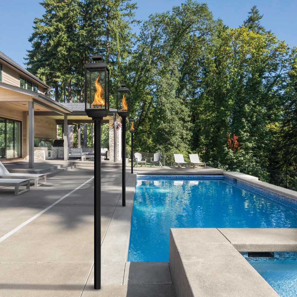 Outdoor gas lantern on a tall dark post with glowing flame behind glass