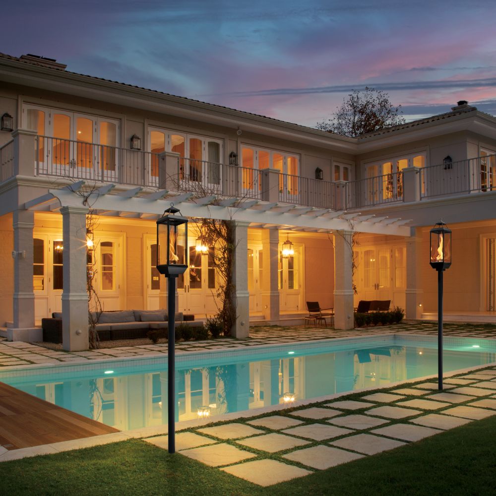 Outdoor gas lantern posts with glowing flames beside a pool
