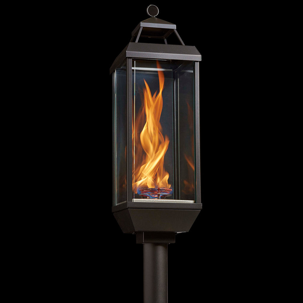 Outdoor gas lantern torch head with burning flame inside clear glass panel
