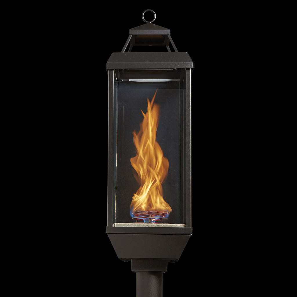 Outdoor gas lantern torch head with burning flame inside clear glass panel and top ring