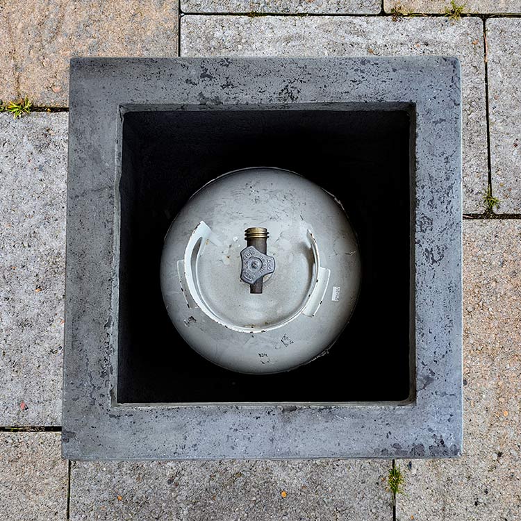 Square concrete propane enclosure opening with round burner insert, gray interior