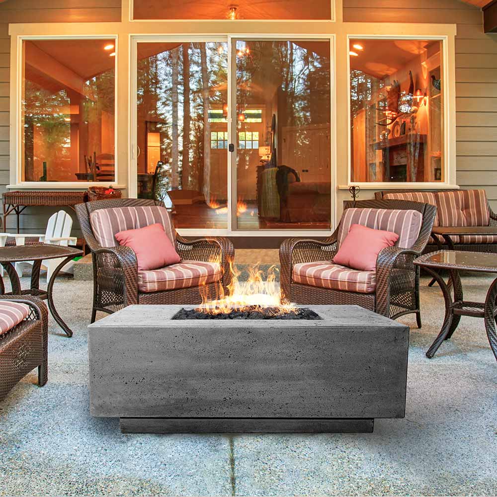 Concrete gas fire pit with flames and square burner opening on a patio