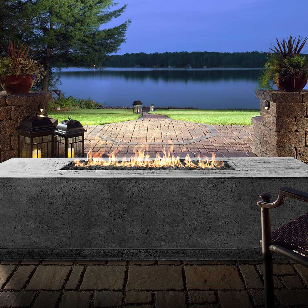 Gray concrete gas fire pit with flames across the rectangular burner opening.